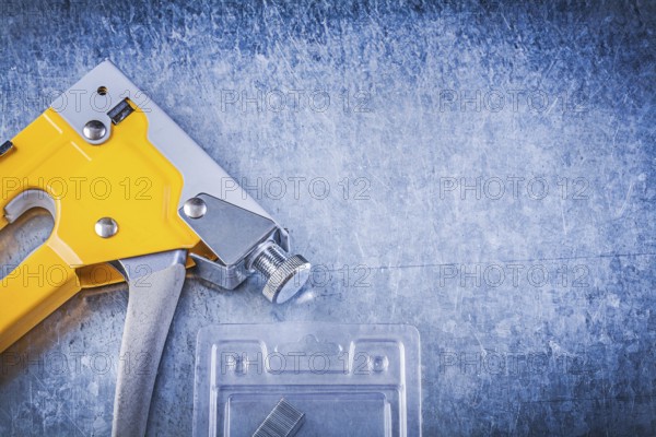 Set of stapler gun chrome staples on scratched metallic background