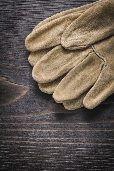 Pair of leather working gloves on vintage wooden board close up view construction concept