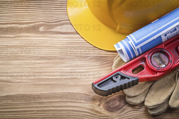 Building helmet protective gloves construction level blueprint on wooden board