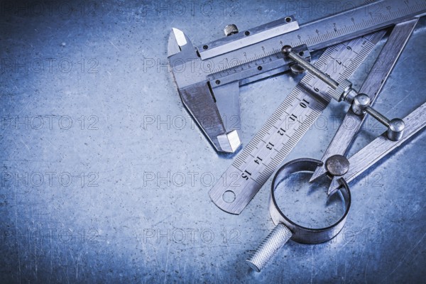 Metal ruler slide caliper construction pair of compasses on metallic background
