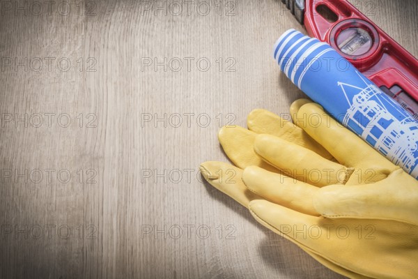 Pair of safety gloves construction level blue engineering drawings on wooden board