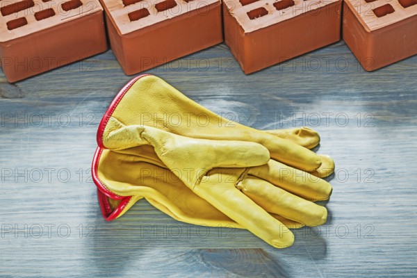 Orange bricks yellow safety gloves on wooden board bricklaying concept