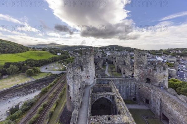 Conwy Castle, medieval castle with towers and surrounding town in a green landscape under a cloudy sky, Conwy, Wales, Great Britain