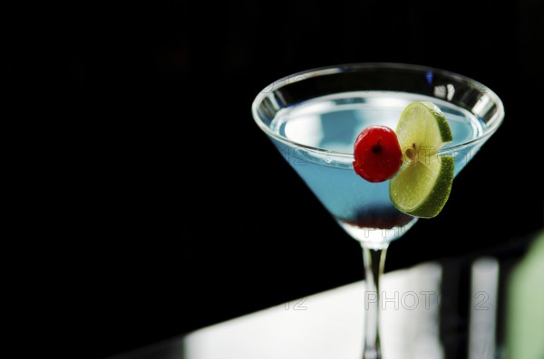 Blue cocktail drink with cherry and lime