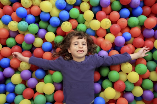 Colorful balls funny park little girl lying gesturing happy