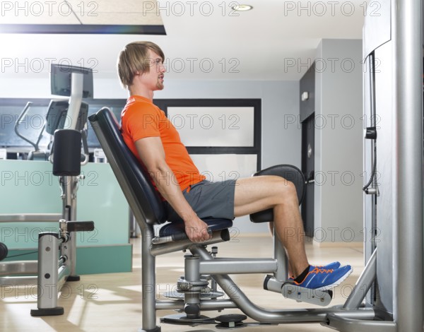 Hip abduction blond man exercise at gym indoor closing legs workout