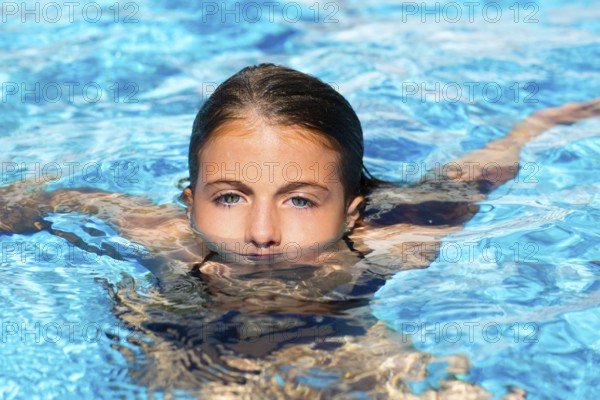 Beautiful blue eyes kid girl at the pool with face in water surface
