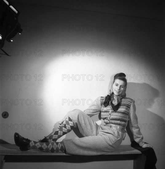 Fashion of 1946. A woman pictured wearing the typical fashion of the postwar era. She is dressed in this year's fashion and clothing for outdoor, sports and leisure use. The trousers are made of strong and durable fabric and she is wearing a warm knitted long-sleeved jumper. She has a scarf around her head. Kristoffersson ref Y68-4