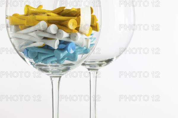 Two glasses of wine and golf equipments on the glass desk