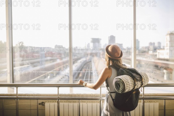Traveler Rear view woman standing at the window in hall Train Station departure with backpack, Selective focus, Travel concept. transportation concept. Theme travel public transport