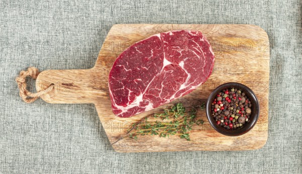 Steak made from fresh beef, with herbs and various spices, on a wooden chopping board, ready to cook, no people