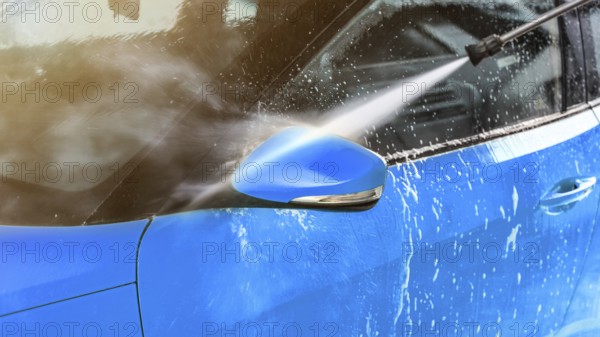 Side mirror of blue car washed in self serve carwash, jet water sprays from high pressure nozzle, Liptovsky Mikulas, Slovakia, Europe
