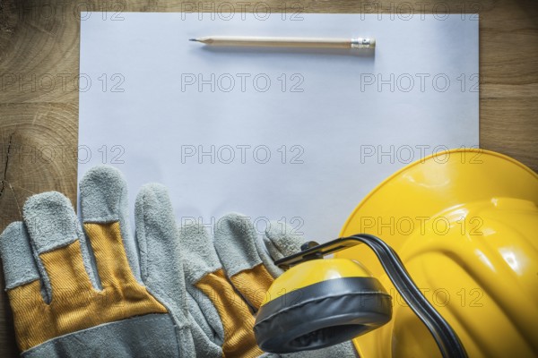 Pencil paper protective gloves hard hat earmuffs on wooden board