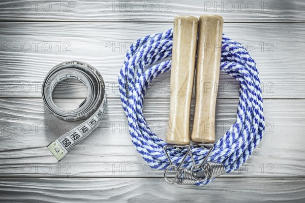 Rolled skipping rope tape measure on wooden board fitness concept