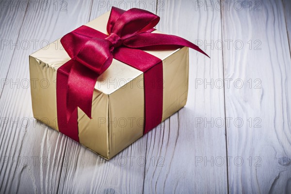 Present box in glittery paper on wooden board holidays concept