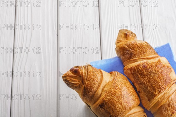 Two croissants on old white wooden boards with copyspace