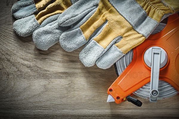 Pair of protective gloves tape measure on wooden board