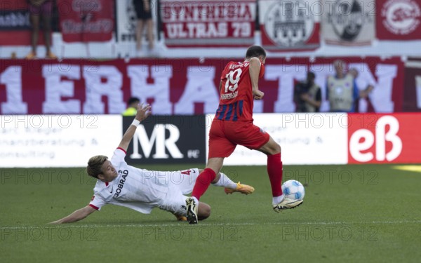 Football match, Ritsu DOAN SC Freiburg left, lying down, tries to separate Jonas FÖHRENBACH 1.FC Heidenheim from the ball, Voith-Arena football stadium, Heidenheim