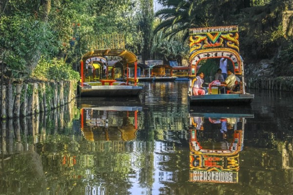 Mexico City, Mexico. Jan 11, 2024. A couple of Trajinera a gondola style boats, or colourful rafts gliding along the Xochimilco canals, with tourists enjoying the ride