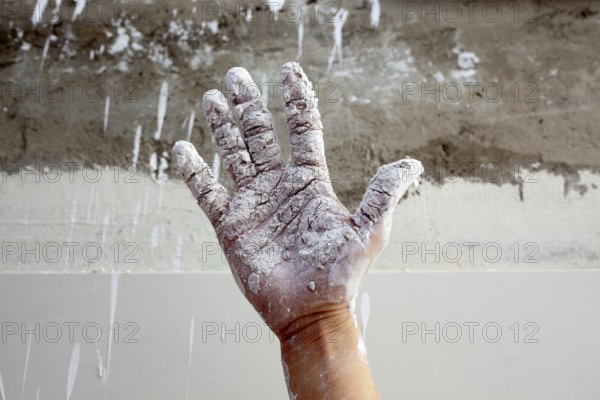 Astist plastering man hand with white dried cracked plaster texture in fingers