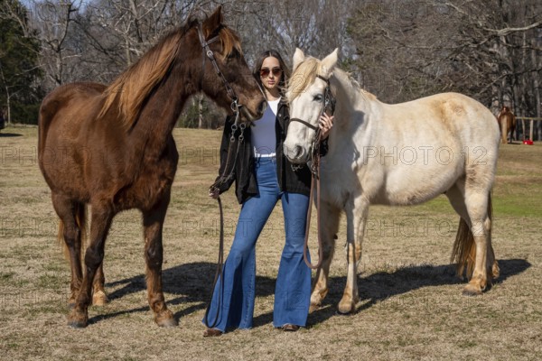 A beautiful brunette cowgirl poses with her horse before a ride in the countryside