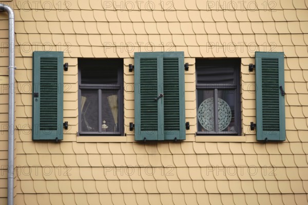 Open shutters on a striking façade of yellow shingles