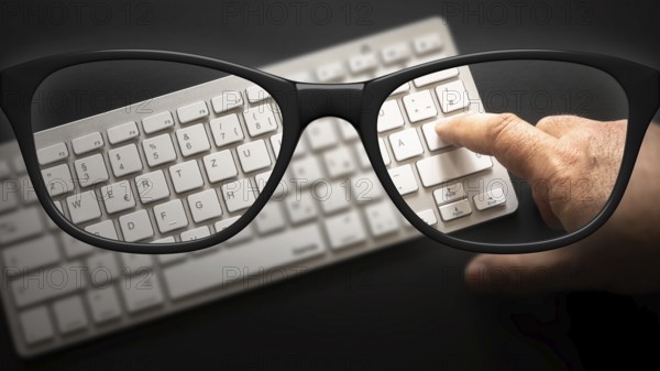 Some black glasses with keyboard sharp and blurred