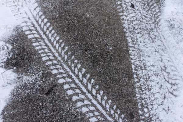 Tyre tracks on snow-covered asphalt, high-contrast texture in winter