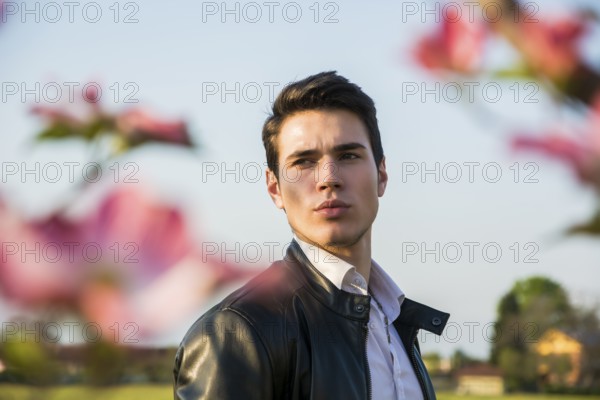 Good looking male model at couuntryside, among flowers, enjoying nature