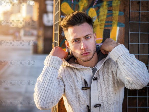 One handsome young man in urban setting in moden city, standing, wearing black coat and scarf in winter day