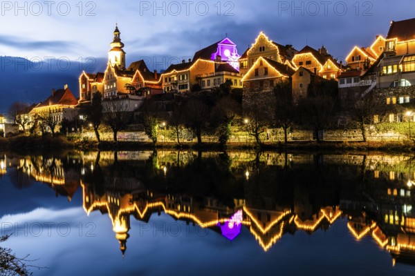 Christmas illuminated house facade of Frohnleiten reflected in the river Mur, blue hour, Frohnleiten, Styria, Austria, Europe