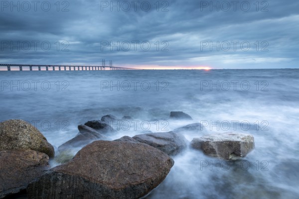 A stormy sea with rocks in the foreground and a bridge in the background, Öresund Bridge, Øresundsbroen, the world's longest cable-stayed bridge, connecting Copenhagen with Malmö