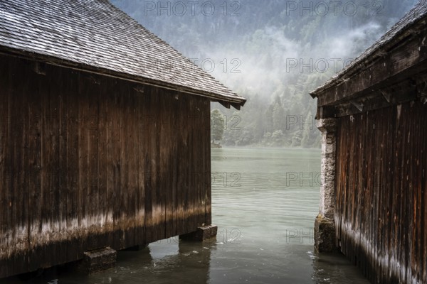 Scenic view of wooden cottages in Konigssee lake a misty summer day in Konigssee lake a misty summer day
