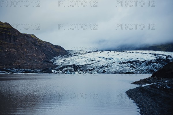 Expansive glacial view with mountains towering over a vast cold lake under a cloudy sky, iceberg, glacier, snow, ice rock, ice diamont, glacier lagoon, nature, snow, Iceland, Europe