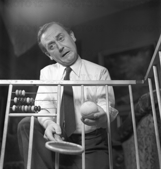 Father in the 1940s. Actor Åke Söderblom, 1910-1965 tries his best at amusing his son from outside the playpen. Sweden 1949 AN92-4