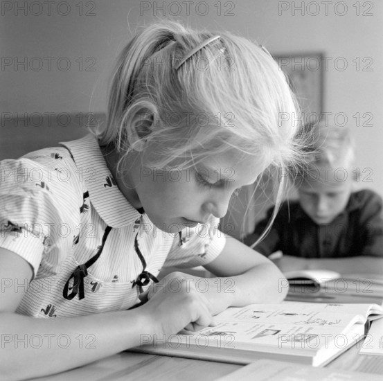 School in the 1950s. A girl is seen sitting at her desk in the classroom reading from the schoolbook in front of her. Sweden 1957 Conard ref 3538
