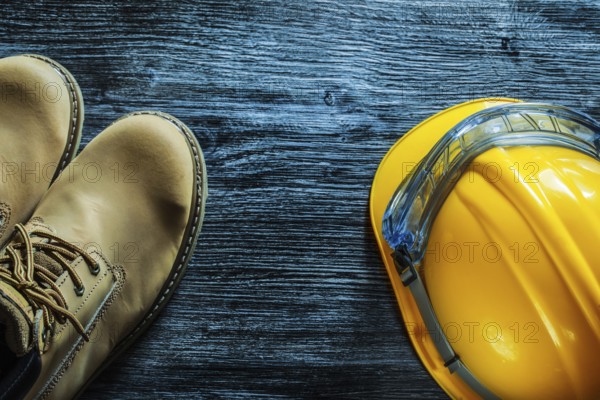 Safety boots building helmet goggles on vintage wooden board