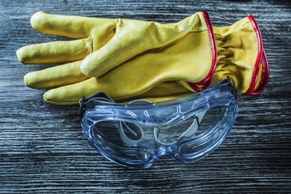 Protective leather gloves glasses on wooden board