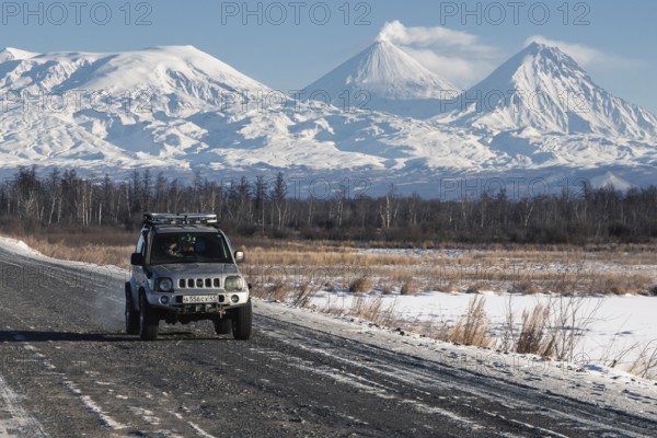 Japanese Sport Utility Vehicle Suzuki Jimny driving along road on background beautiful winter landscape travel destinations, active Kluchevskoy Volcano. Kamchatka Peninsula, Russia, January 7, 2016, Europe