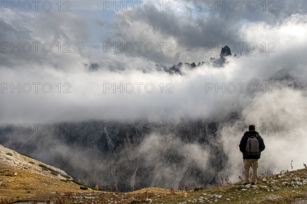Man arms outstretched at sunrise enjoying landscape freedom and life. Tre cime di lavadero Italian Alps Italy