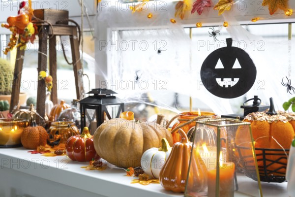 Festive decor of the house on the windowsill for Halloween, pumpkins, Jack o lanterns, skulls, cobwebs, spiders, skeletons, candles and a garland, a cozy and terrible mood