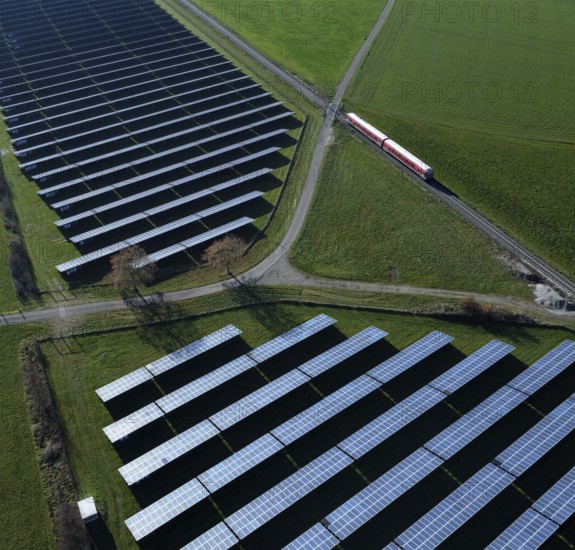 Red local railway runs on a non-electrified railway line next to a solar park through green meadows, drone shot, Upper Bavaria, Bavaria, Germany, Europe