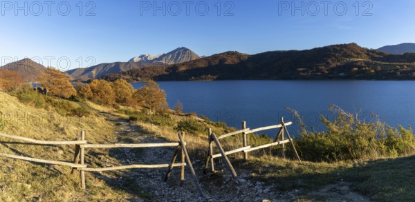 A wooden fence and hiking trail on the banks of Campotosto Lake in the mountains of Abruzzo in Italy