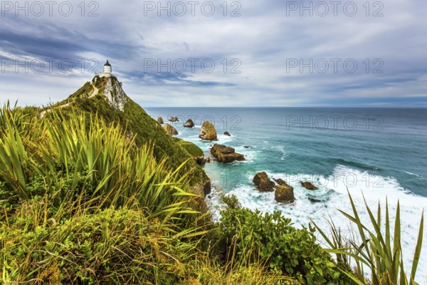 Nugget Point Lighthouse on the picturesque Cape Nugget. South Island, New Zealand. The coast of the Pacific Ocean. The concept of active, environmental and photo tourism