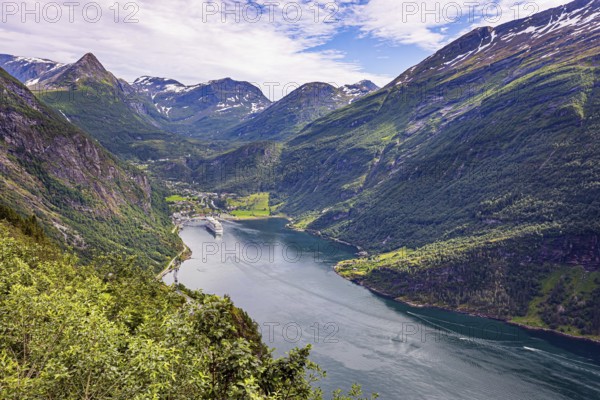 The largest, most beautiful and famous Norwegian fjord Geiranger. Snow-white ocean liner is moored at the pier. Northern Europe. Summer trip to Norway