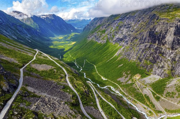 The serpentine road meanders on the green slopes of the canyon. Filming from a drone. Summer trip to Norway. Trollstigen - the most popular tourist spot in Norway