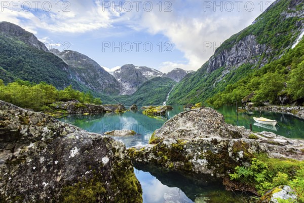 Journey to the fabulous northern country in the middle of summer. Picturesque small boat is moored to the shore. The mountain lake Bondhuswatnet. Evening soft twilight. Norway