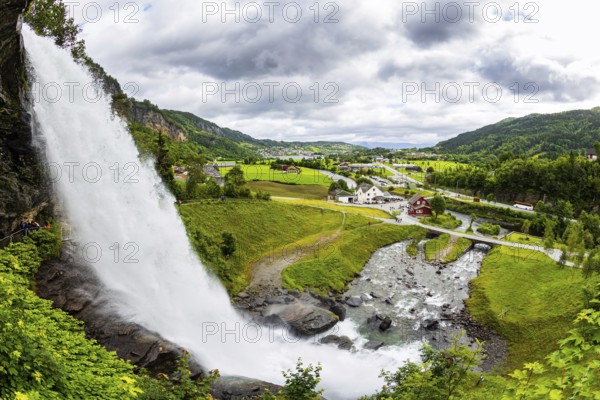 Huge bubbling waterfall Steinsdalsfossen. Summer day in the mountains of Norway. Exciting adventure in the north. Picturesque green country