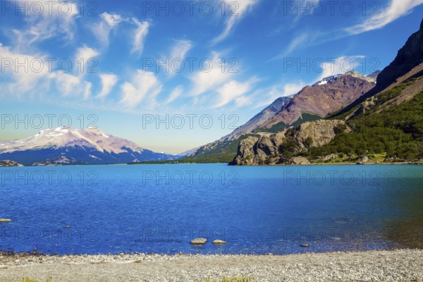 Huge lake with azure water rocky beach by the lake. Patagonia. Pampas surround snow-capped mountains. Los Glaciares is Argentina's most beautiful natural park