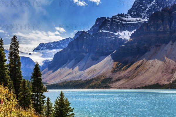 The Rockies of Canada. The picturesque huge and deep Lake Bow is surrounded by cliffs and glaciers. The wind drives lush cumulus clouds. The concept of active and photo tourism